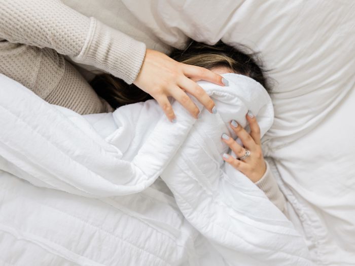 Woman can't get to sleep, and has poor sleep, with covers over face