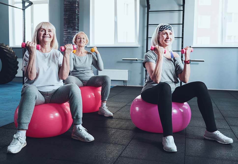 Three women exercising with weights and balance fitness balls.