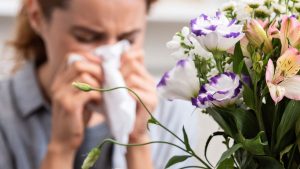 Woman with allergies feeling symptoms near flowers
